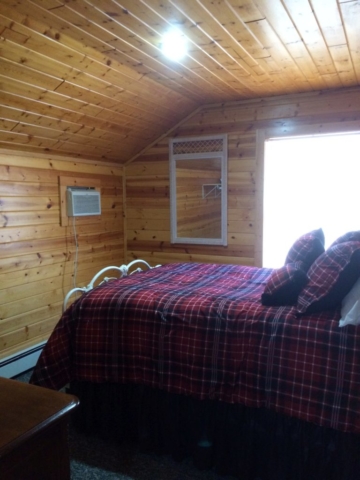 Second floor bedroom at Torch Lake Lodge. Features antique bed and view of fire pit.