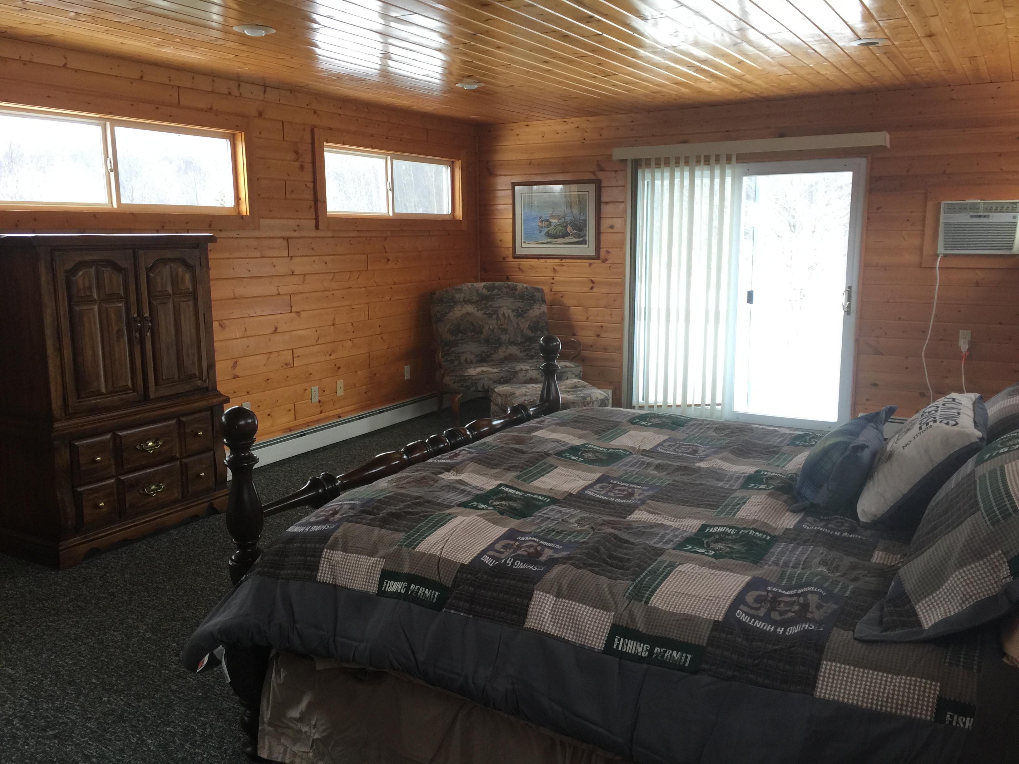 Third floor master bedroom at Torch Lake Lodge. Bedroom includes private deck overlooking trees and fire pit.